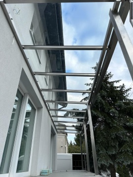 Zadaszenie balkonu w domu jednorodzinnym ze stali i szkła.