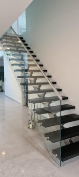 Czarne schody kamienne na stalowej konstrukcji z szklaną balustradą