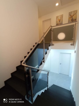 Czarne nowoczesne schody wewnętrzne z czarną, szklaną balustradą